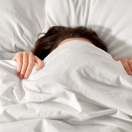 Frau eingekuschelt in ein Bett.