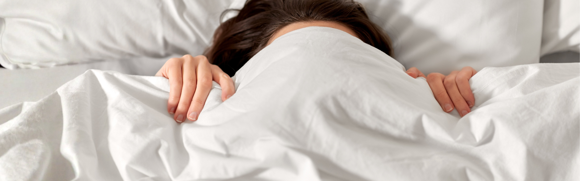 Frau liegt eingekuschelt in einem Bett.