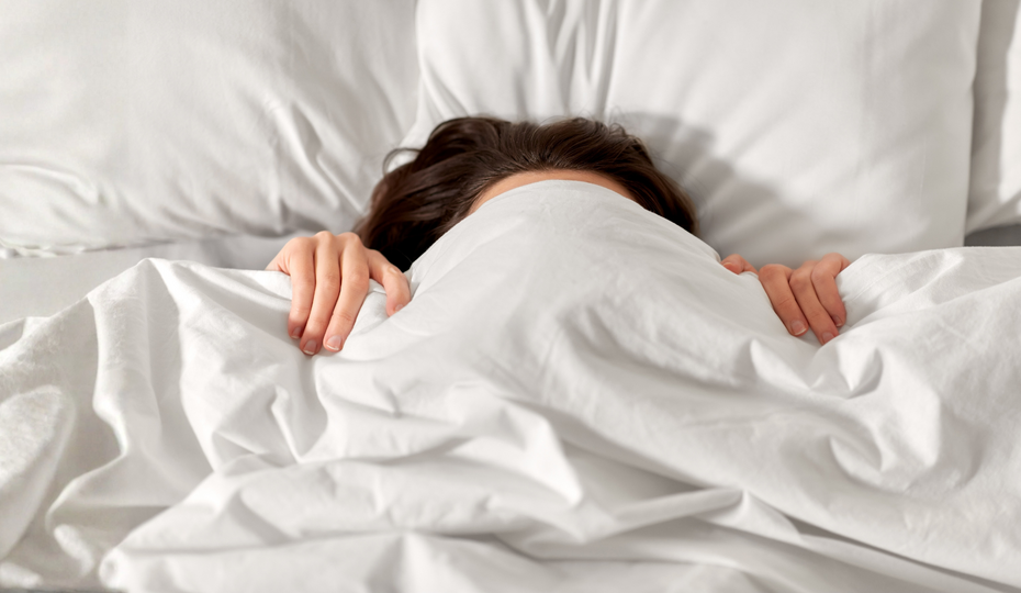 Frau eingekuschelt in ein Bett.