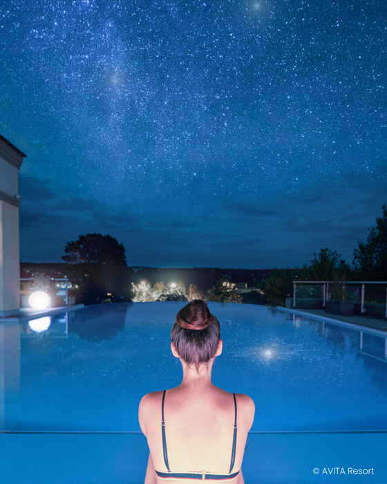 Frau im Infinity Pool bei Nacht.