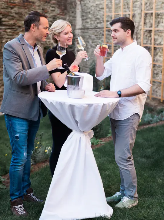 Seminargäste unterhalten sich bei einem Glas Wein im Clusius Gartenhof